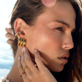 Woman wearing gold earrings and ear cuffs