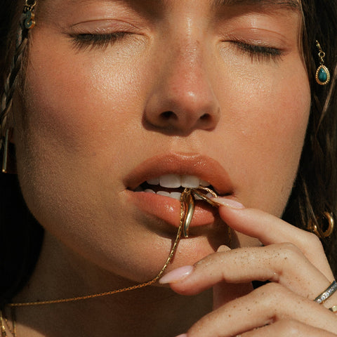 Close-up of a woman wearing gold jewelry with a blurred background