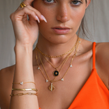 model wearing matchin bracelets and necklaces. Layered necklaced. Gold bracelets, gold necklaces.