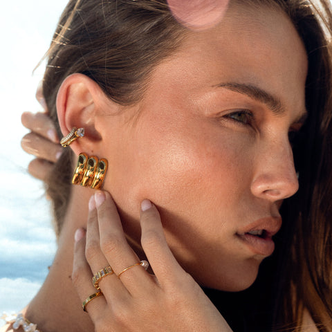 Woman wearing gold earrings and ear cuffs