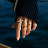 Hand with multiple waterproof hammered rings by the sea